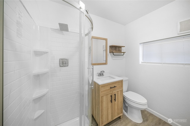 bathroom with toilet, vanity, wood-type flooring, and tiled shower