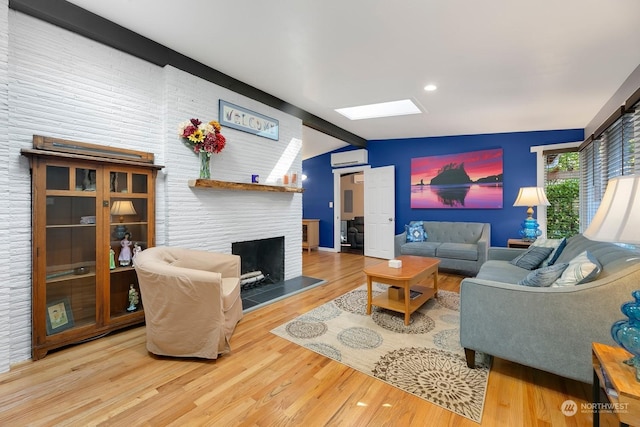 living room featuring a wall mounted air conditioner, hardwood / wood-style floors, and vaulted ceiling with skylight