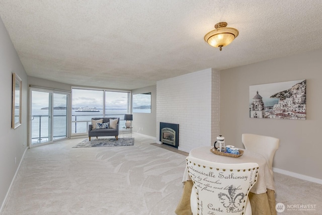 living room with light carpet, a fireplace, a textured ceiling, and baseboards