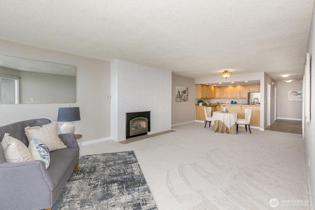 living area with light colored carpet, a fireplace, a textured ceiling, and baseboards