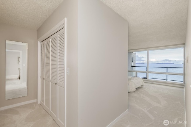 corridor with carpet flooring, baseboards, and a textured ceiling