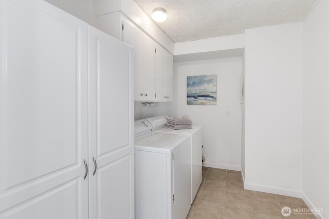 clothes washing area with baseboards, washing machine and dryer, light tile patterned floors, cabinet space, and a textured ceiling