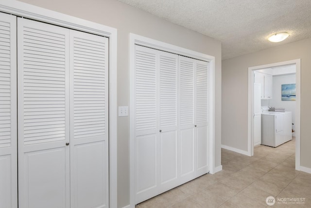 corridor featuring light tile patterned floors, baseboards, a textured ceiling, and washer and clothes dryer