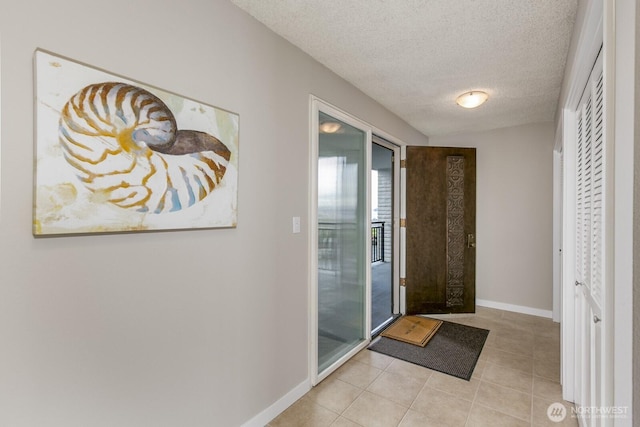 foyer with light tile patterned flooring, a textured ceiling, and baseboards