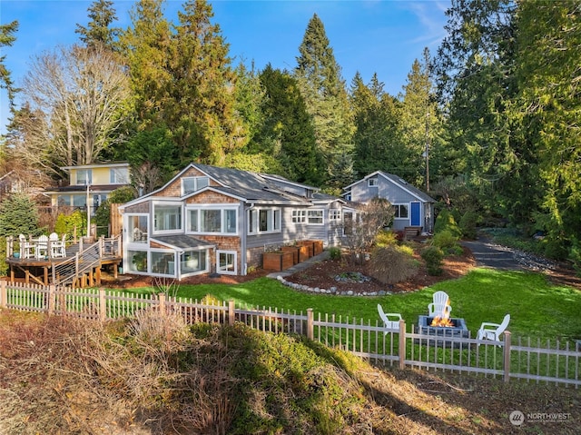 back of property featuring a lawn, a fenced backyard, a sunroom, and an outdoor fire pit