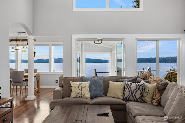 living room with a high ceiling, a water view, and dark wood-type flooring