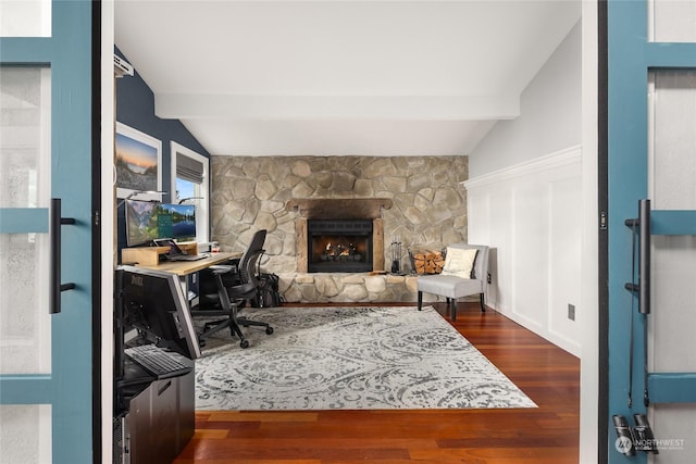 office with vaulted ceiling with beams, dark hardwood / wood-style flooring, and a stone fireplace