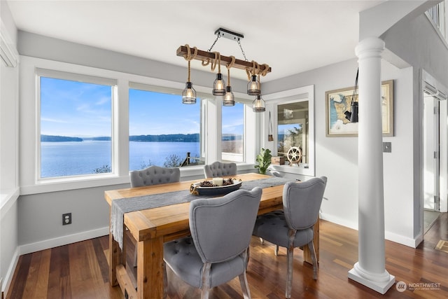 dining area featuring a water view, ornate columns, and dark hardwood / wood-style floors