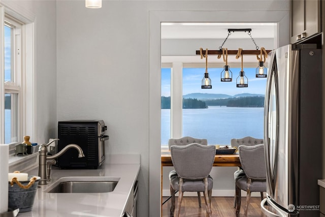 dining area featuring hardwood / wood-style flooring, a water and mountain view, and sink