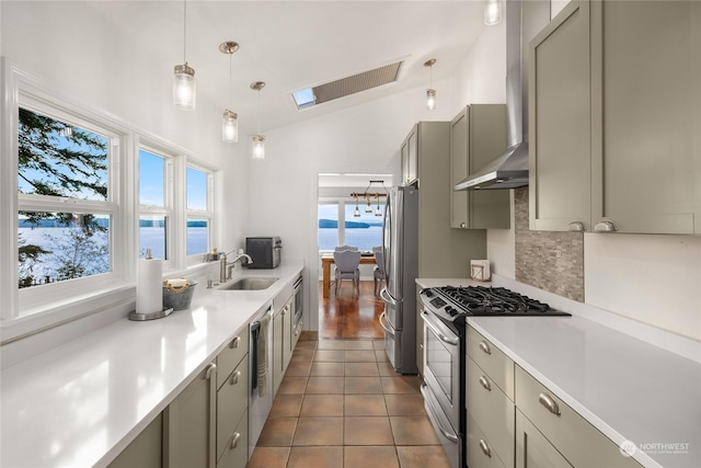 kitchen with a water view, wall chimney range hood, vaulted ceiling with skylight, gray cabinets, and stainless steel appliances