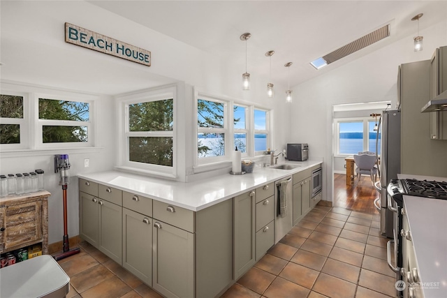 kitchen featuring a water view, vaulted ceiling, gray cabinets, decorative light fixtures, and stainless steel appliances