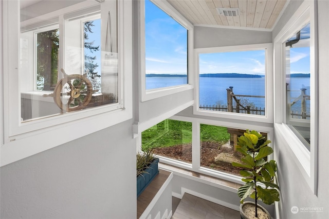 sunroom / solarium with a water view, wood ceiling, and a wealth of natural light