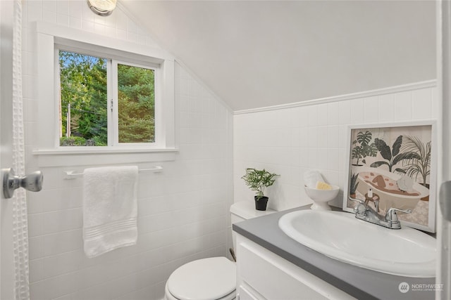 bathroom featuring vanity, toilet, tile walls, and lofted ceiling