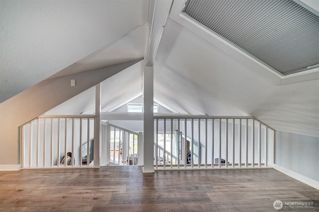 bonus room featuring baseboards, lofted ceiling with beams, and wood finished floors