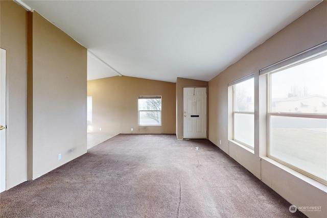 carpeted spare room featuring lofted ceiling