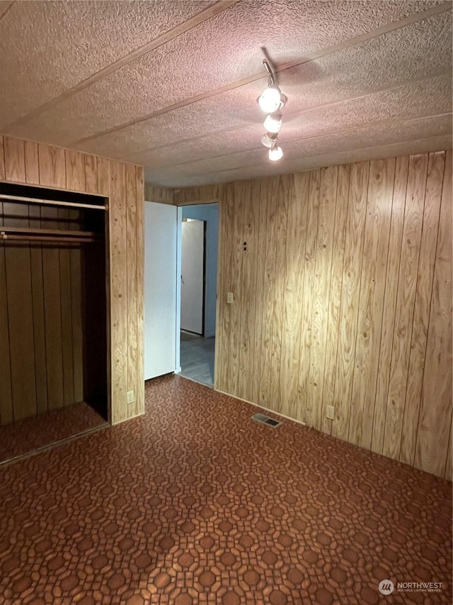 unfurnished room featuring wood walls and a textured ceiling