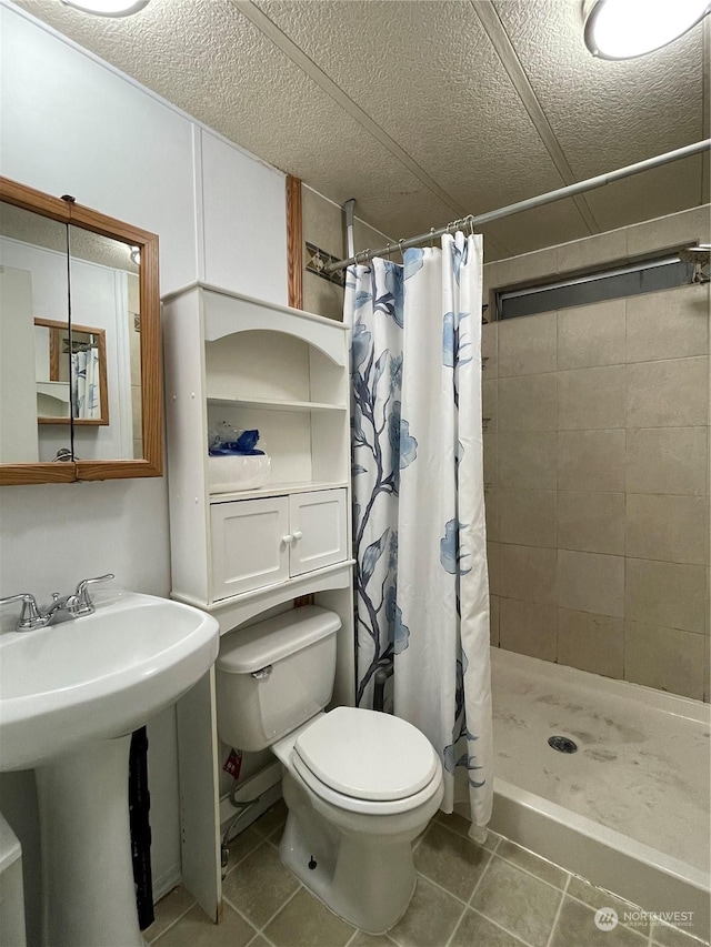 bathroom with curtained shower, tile patterned flooring, a textured ceiling, and toilet