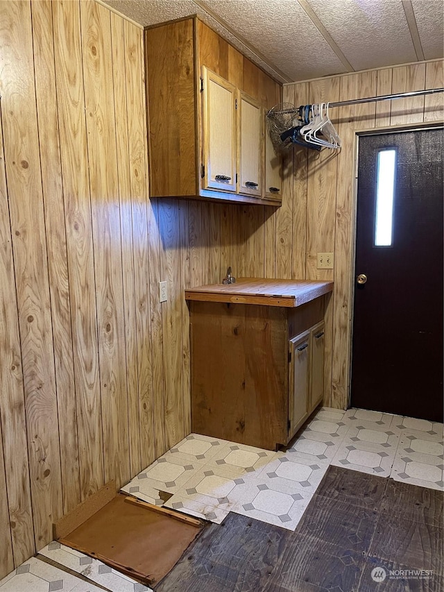 washroom featuring wooden walls and a textured ceiling