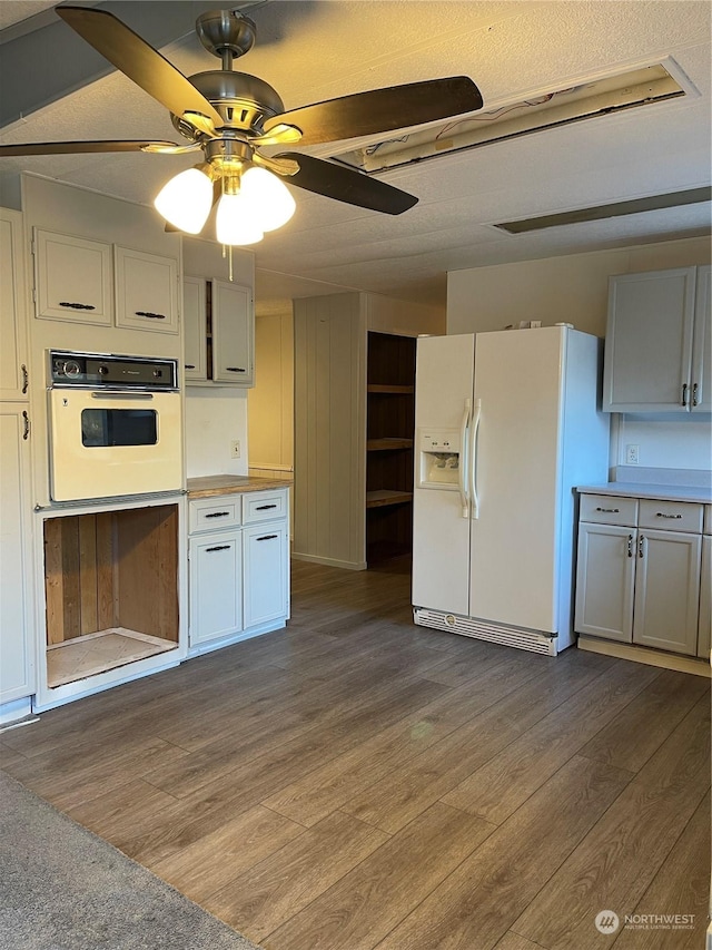 kitchen featuring ceiling fan, hardwood / wood-style floors, a textured ceiling, white appliances, and white cabinets