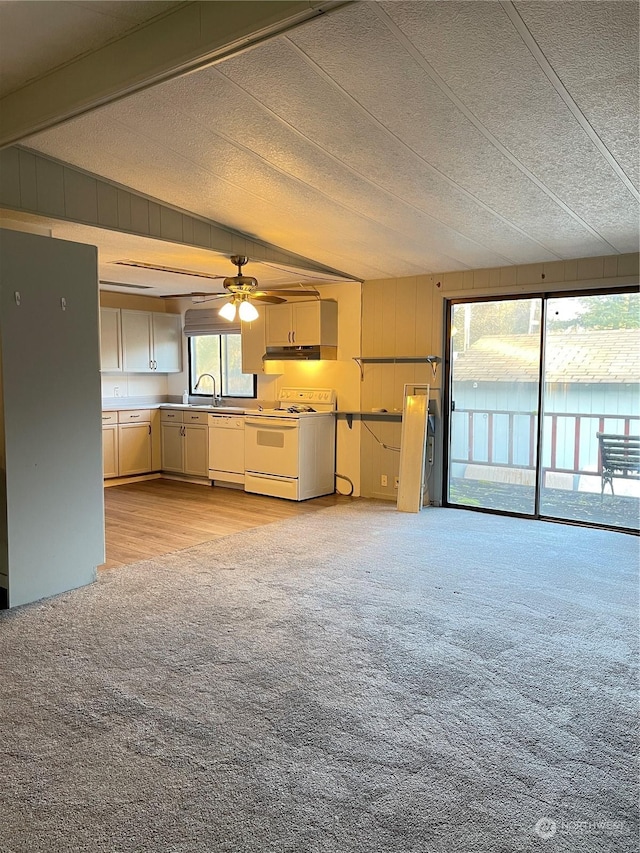 unfurnished living room with ceiling fan, sink, light colored carpet, and a textured ceiling