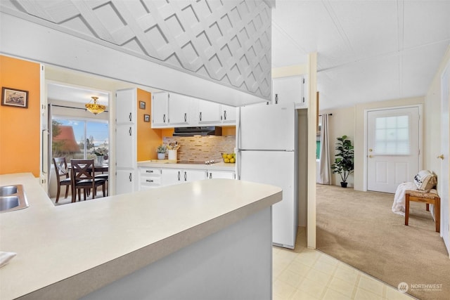 kitchen with black electric cooktop, extractor fan, sink, white fridge, and white cabinetry