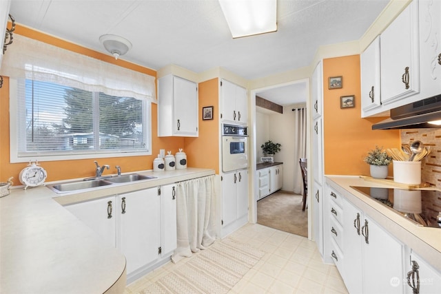 kitchen featuring white cabinets, cooktop, oven, and sink