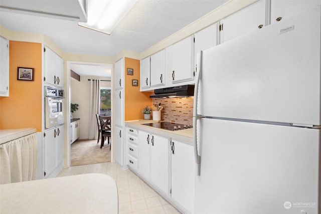 kitchen with stainless steel oven, backsplash, white cabinets, black electric cooktop, and white fridge