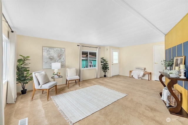 sitting room with beam ceiling and light carpet