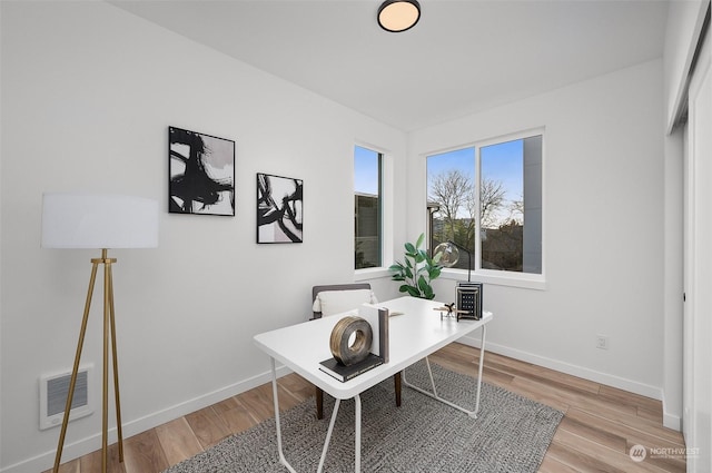 home office with light hardwood / wood-style flooring