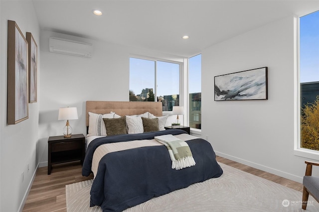 bedroom with wood-type flooring, an AC wall unit, and multiple windows