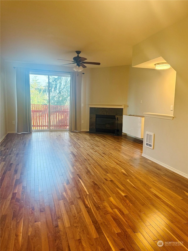 unfurnished living room featuring a tile fireplace, ceiling fan, hardwood / wood-style floors, and heating unit