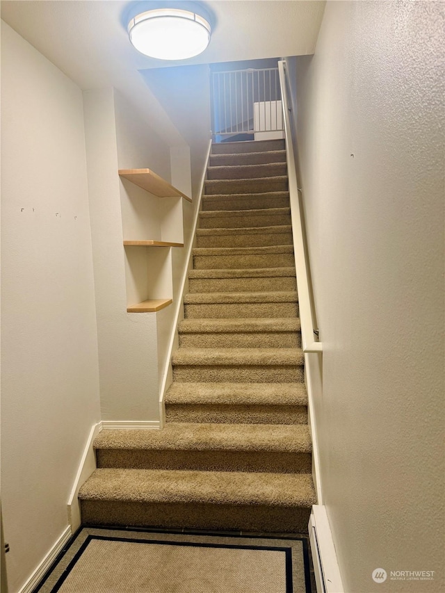 stairway with carpet floors and baseboard heating