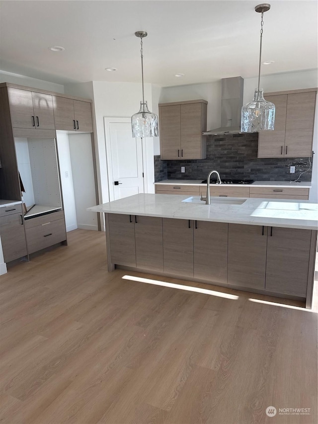 kitchen featuring decorative backsplash, pendant lighting, light hardwood / wood-style flooring, and wall chimney range hood