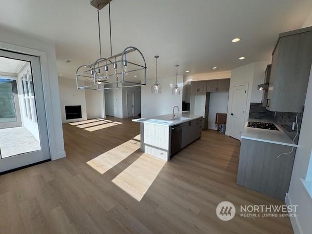 kitchen featuring sink, dark hardwood / wood-style floors, black appliances, and an island with sink