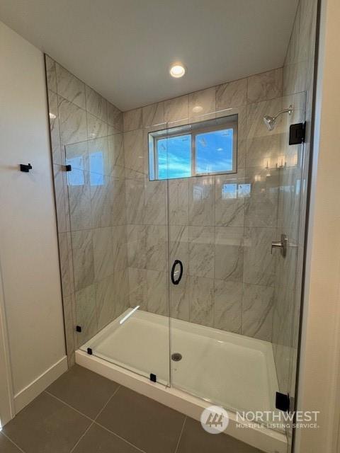 bathroom with an enclosed shower and tile patterned flooring