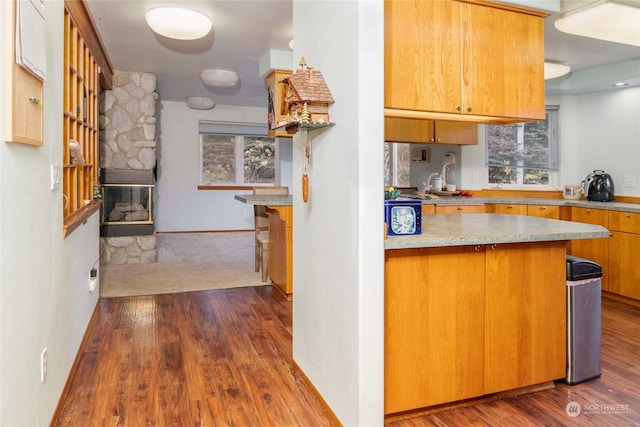 kitchen featuring kitchen peninsula, a fireplace, and dark wood-type flooring