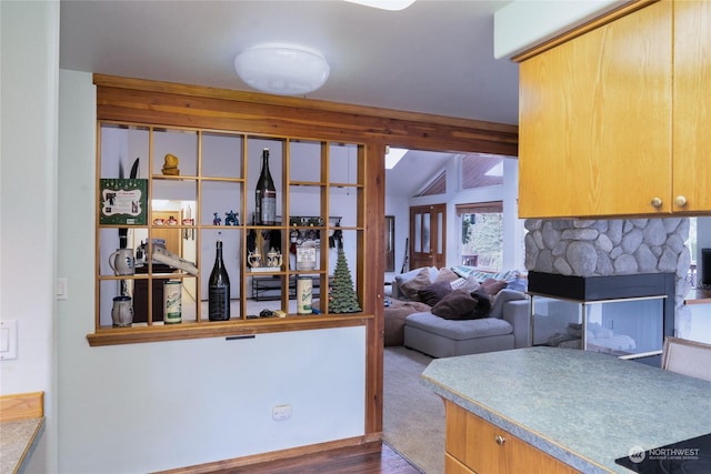 kitchen featuring dark colored carpet and a stone fireplace