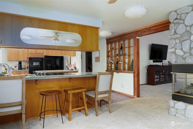 kitchen featuring a kitchen bar, kitchen peninsula, light colored carpet, and black appliances