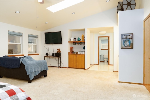 bedroom featuring light colored carpet, ensuite bath, and lofted ceiling with skylight