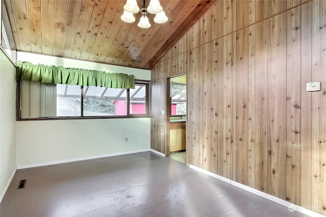 spare room featuring wood walls, lofted ceiling, wood ceiling, and concrete floors