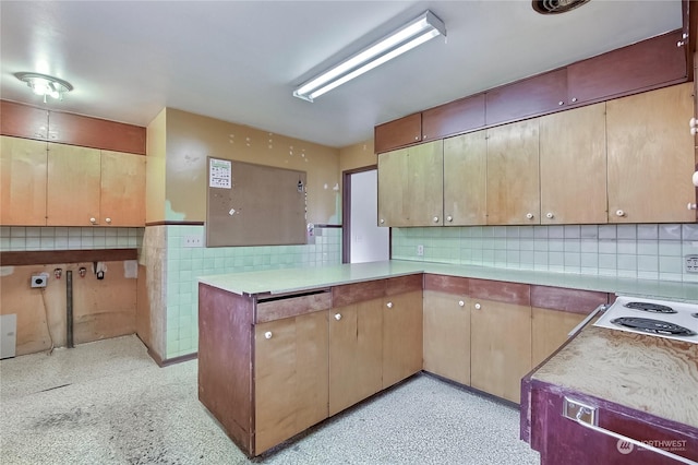 kitchen featuring white cooktop, kitchen peninsula, and tasteful backsplash