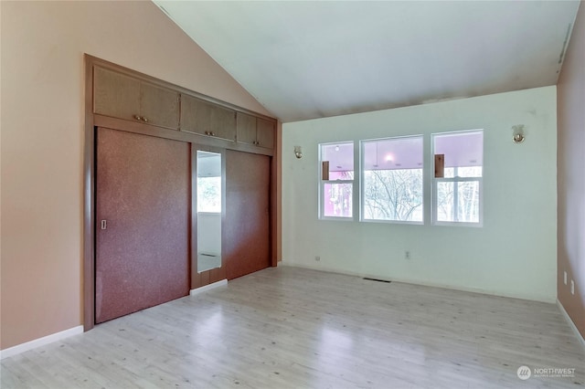 unfurnished bedroom featuring a closet, vaulted ceiling, and light hardwood / wood-style flooring