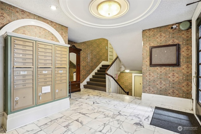 entryway featuring a tray ceiling, a textured ceiling, and a mail area