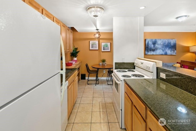 kitchen with light tile patterned floors, white appliances, and dark stone counters