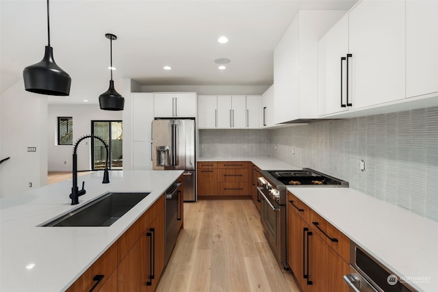 kitchen with white cabinetry, sink, stainless steel appliances, light hardwood / wood-style floors, and decorative light fixtures