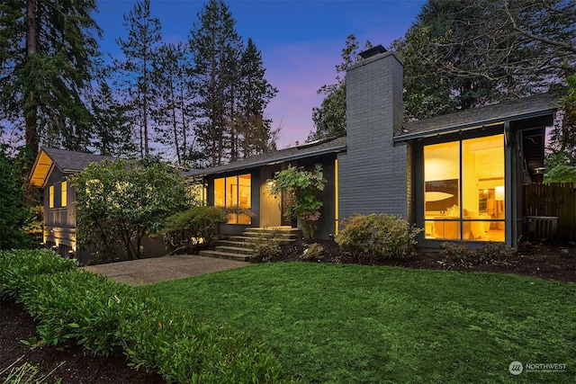 view of front of house featuring a patio, a lawn, and central AC