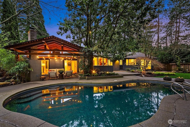 pool at dusk with a patio area and outdoor lounge area