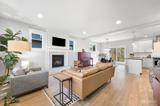 living room featuring light hardwood / wood-style flooring, a notable chandelier, and sink