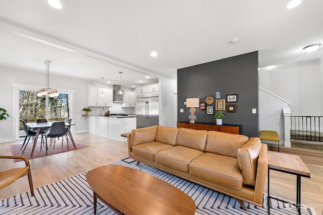 living room with an inviting chandelier, sink, and light hardwood / wood-style flooring