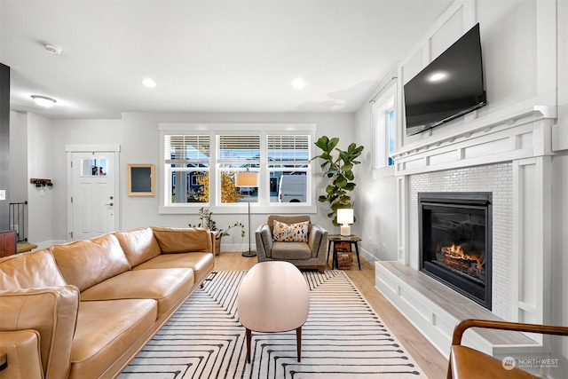 living room with a tile fireplace and light hardwood / wood-style flooring